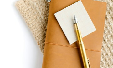 gold and silver pen on brown envelope